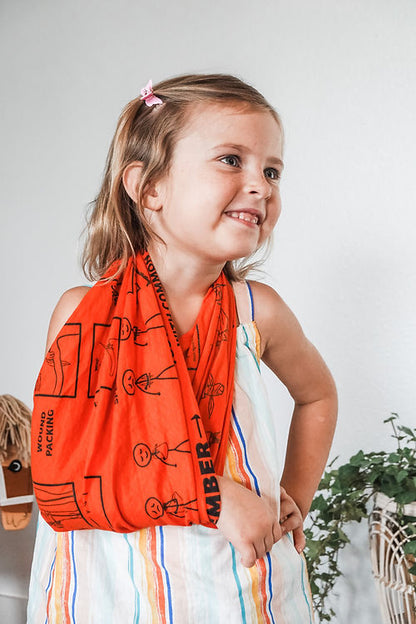 Young girl wearing an orange scarf with black graphics against a white background
