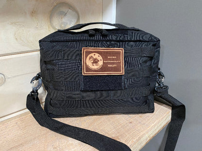 Black tactical bag with a patch on a wooden surface