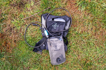 Black hydration pack with water bottle on grass